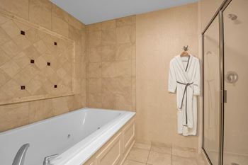 A white bathrobe is hanging on a hook in a bathroom.